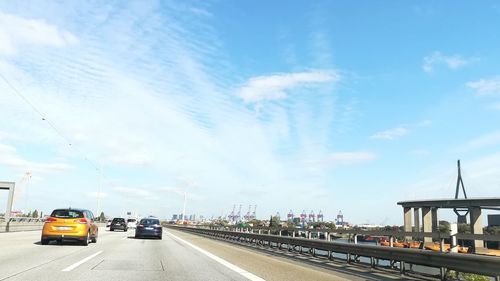 Cars on road against sky in city