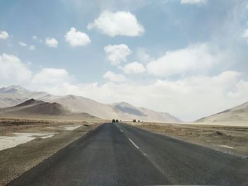 Road leading towards mountains against sky