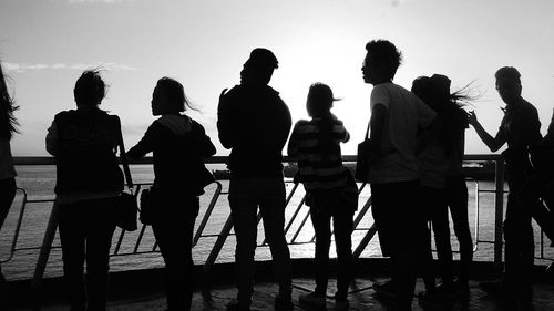 Silhouette people standing by sea against clear sky