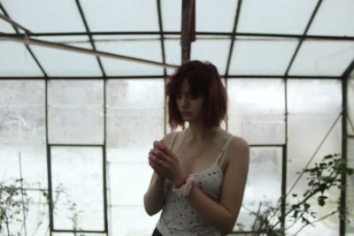 Young woman looking through window