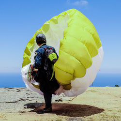 Rear view full length of man with parachute standing on field