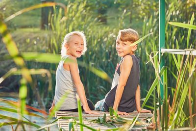 Portrait of siblings sitting on jetty