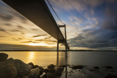 Bridge over sea against sky during sunset