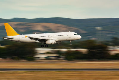 Airplane flying over airport runway against sky