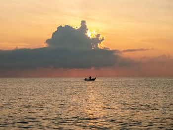 Silhouette person in sea against sky during sunset