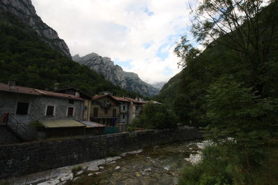 Houses by trees and mountains against sky