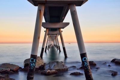 Pier over sea against sky during sunset