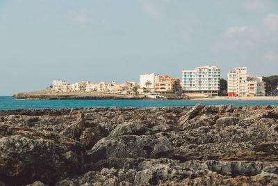 Sea by city against sky