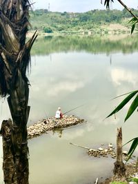 Reflection of men fishing in lake