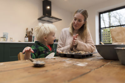 Mother and son by food on table at home