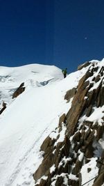 Scenic view of snow covered mountains against clear blue sky