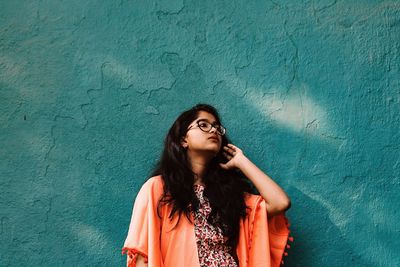 Young woman standing against blue wall