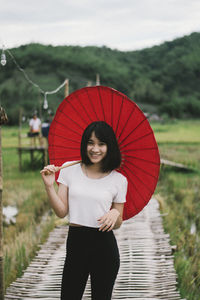 Portrait of woman standing with red umbrella