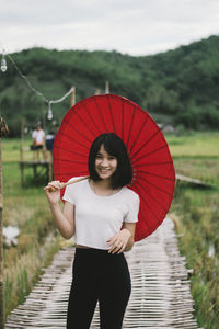 Portrait of smiling woman with umbrella standing on boardwalk