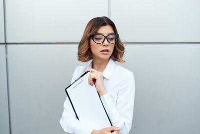 Young woman standing against white wall