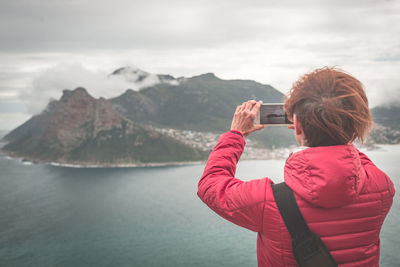 Rear view of woman photographing lake