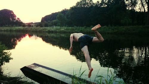 Full length of shirtless man jumping over lake