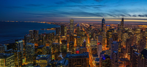 Aerial view of illuminated buildings in city at dusk