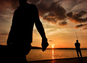 Silhouette people at beach during sunset