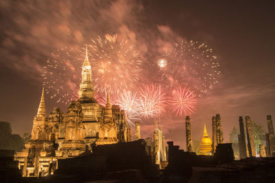 Firework display in city against sky at night