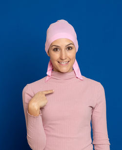 Portrait of a smiling young woman against blue background