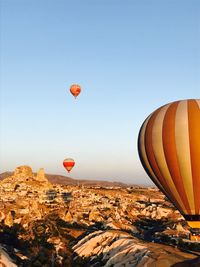 Hot air balloons flying over landscape against clear sky