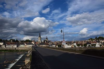 Buildings in town against cloudy sky