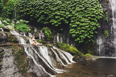 Woman in lotus position doing yoga at waterfall