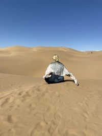 Rear view of man on desert against clear sky