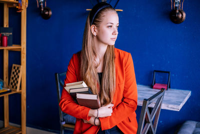 A young woman holds a stack of books. teaching a student according to textbooks.