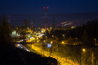 Electricity pylons and illuminated street lights in city at night