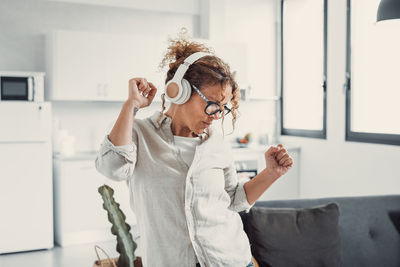 Young woman using mobile phone while standing at home