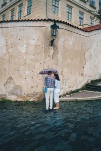 Full length rear view of woman standing against building