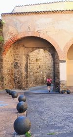 Rear view of woman walking by historic building