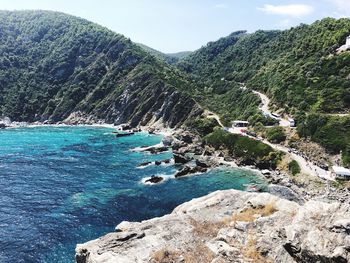 Scenic view of sea by mountain against sky