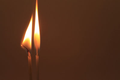 Close-up of lit candle against colored background