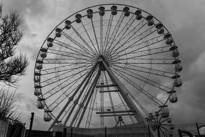 Low angle view of ferris wheel against cloudy sky