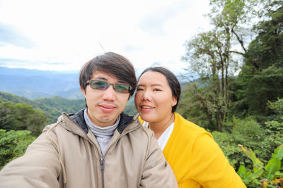 Portrait of smiling friends against trees and sky