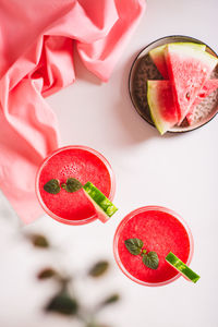 Watermelon lemonade with watermelon pieces in glasses on pink background top and vertical view