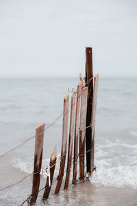 Wooden posts on beach against sky