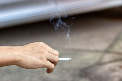 Cropped hand of man smoking cigarette on street