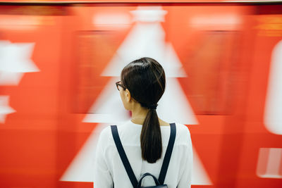 Rear view of woman standing against red wall