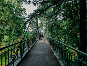People walking on footbridge in forest