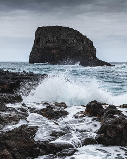 Rock formation on sea shore against sky