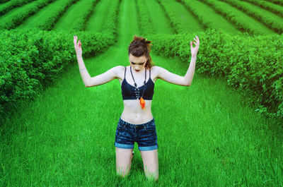 Woman with arms raised kneeling on grassy land