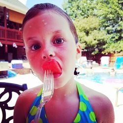 Portrait of girl eating watermelon at poolside