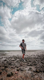 Full length of man standing on beach against sky