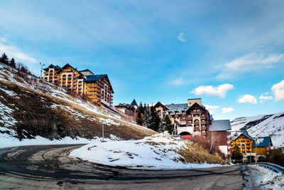 Snow covered houses by buildings against sky