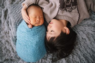 High angle view of cute boy and baby sleeping on bed