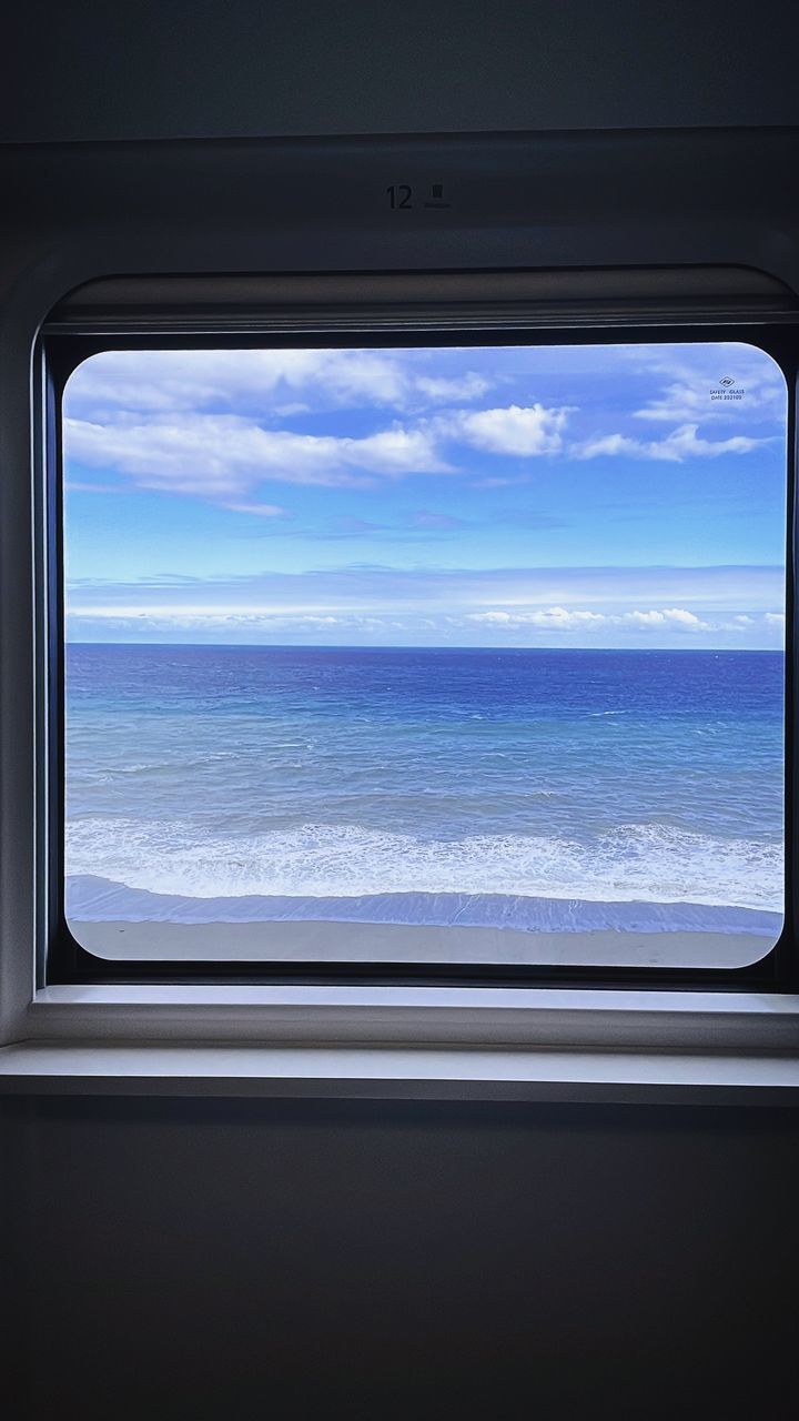 window, sky, cloud, mode of transportation, transportation, vehicle interior, sea, travel, television set, scenics - nature, airplane, horizon, water, nature, glass, no people, television, beauty in nature, blue, air vehicle, day, journey, transparent, outdoors, horizon over water, vacation, cloudscape, flying, holiday, looking through window, trip, technology, land, tranquility, light